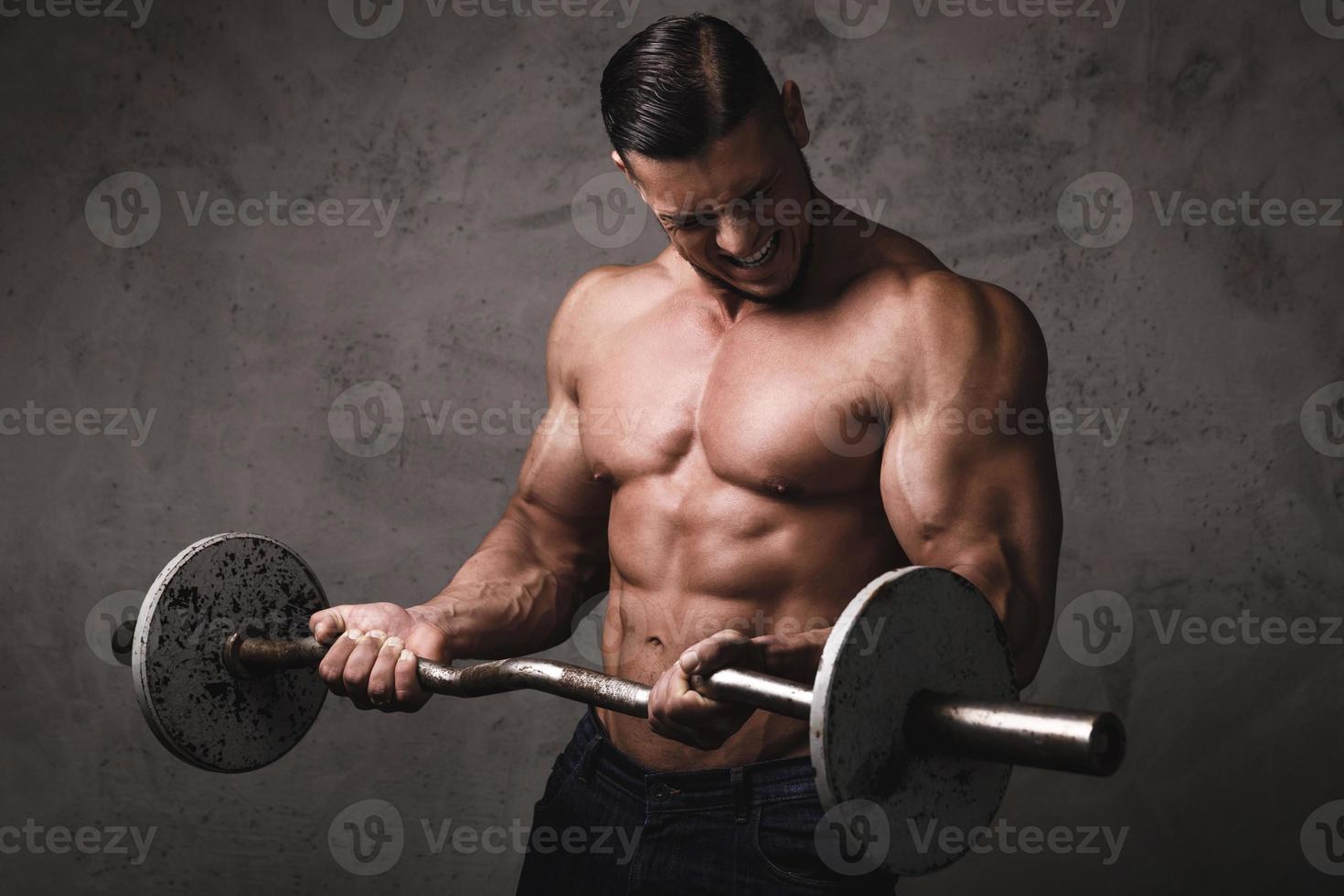 bodybuilder brutal massif faisant des exercices avec des haltères photo