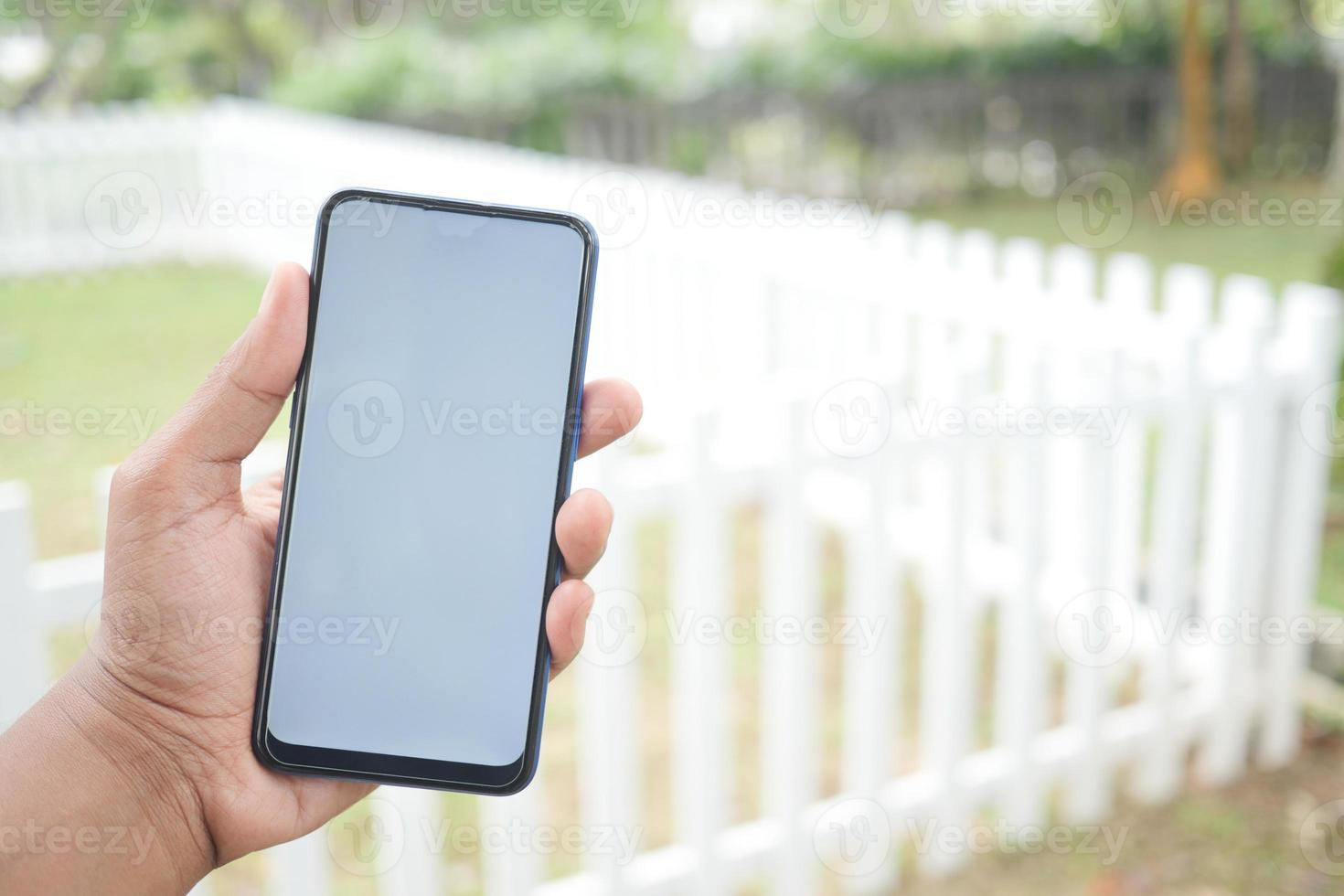 main de jeune homme utilisant un téléphone intelligent avec écran vert contre les bâtiments de la ville photo