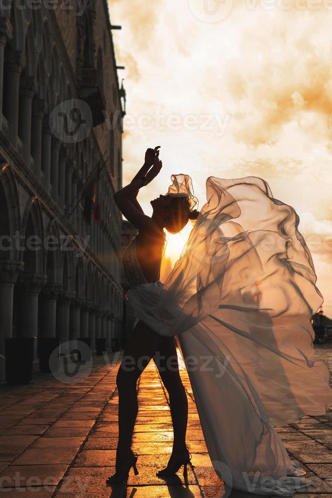 femme portant une belle robe blanche marchant dans une rue de la ville de venise photo