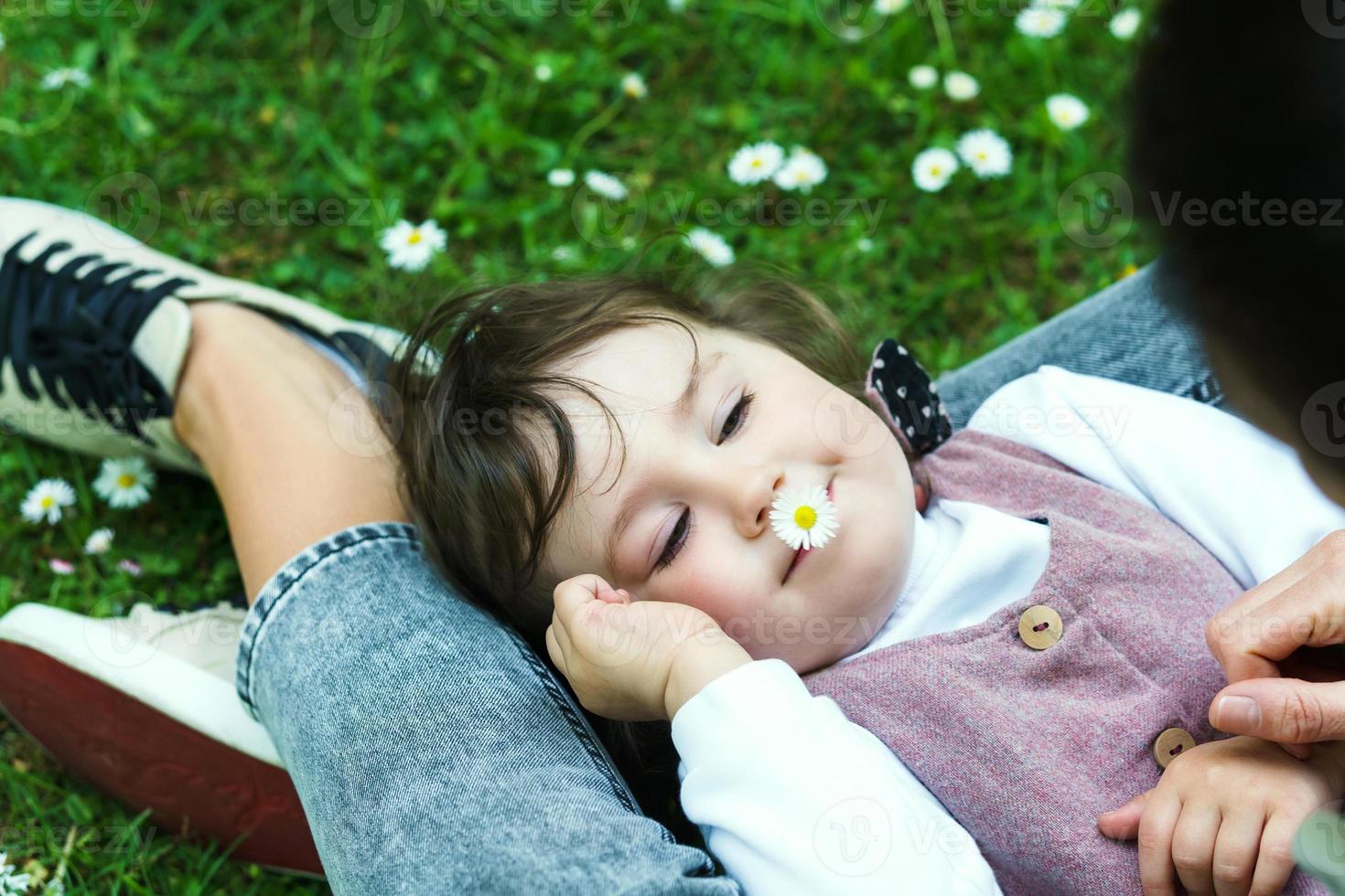 petite fille avec sa mère sont allongées dans un champ de camomille photo