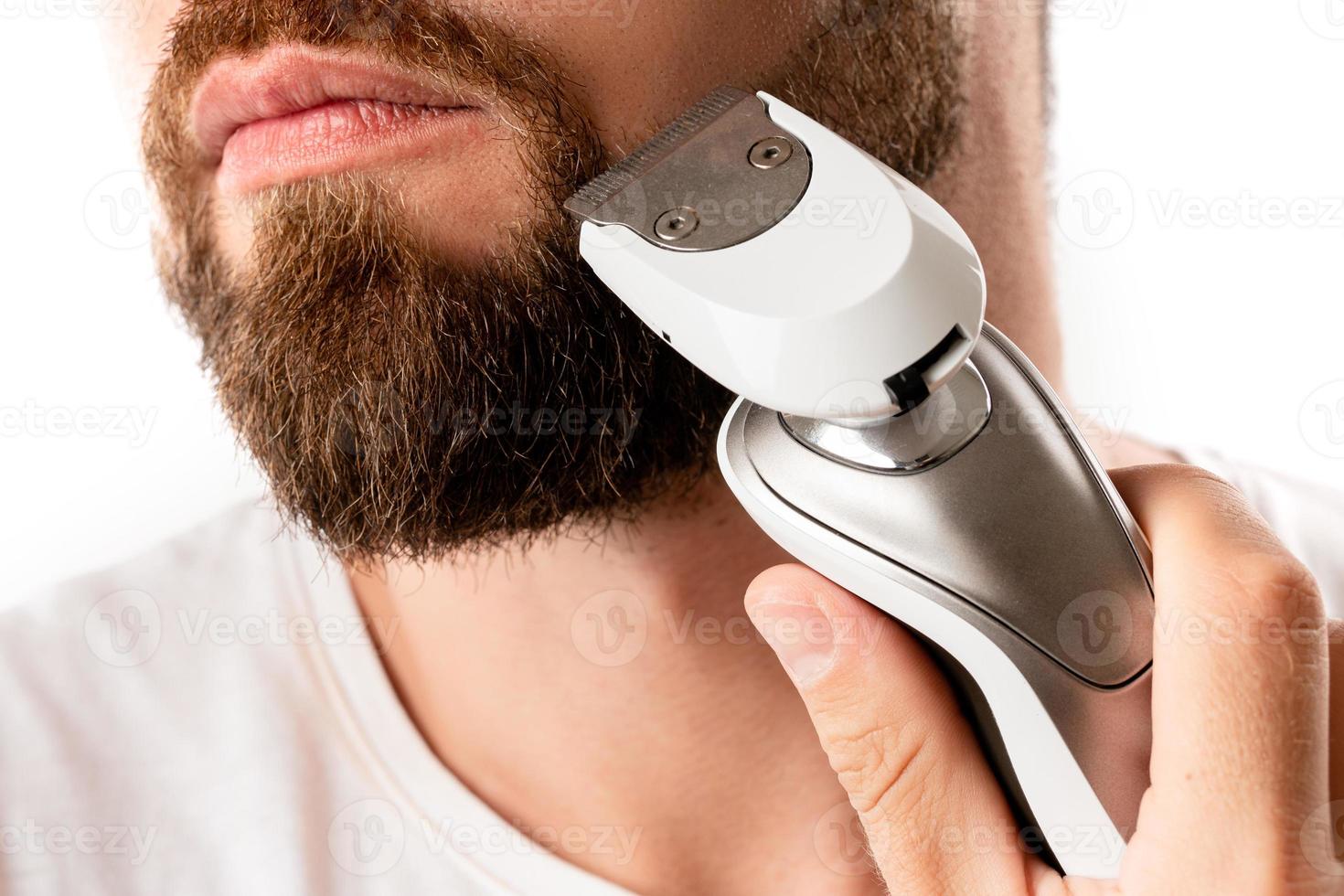 bel homme barbu utilise une tondeuse électrique photo