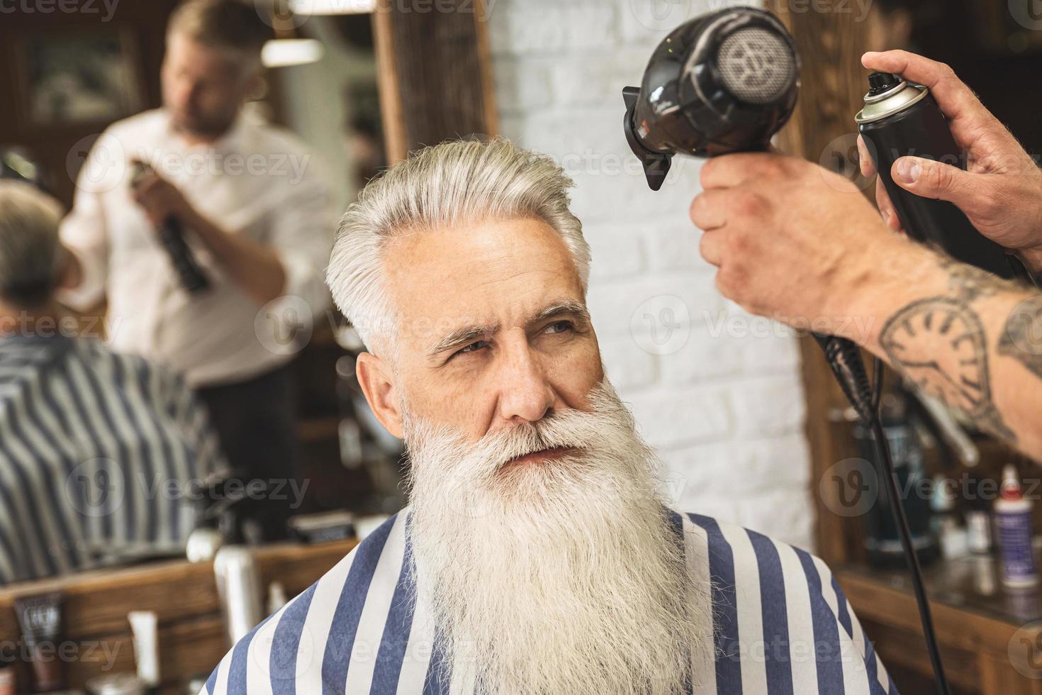 coiffeur faisant une coupe de cheveux élégante pour un beau vieil homme photo