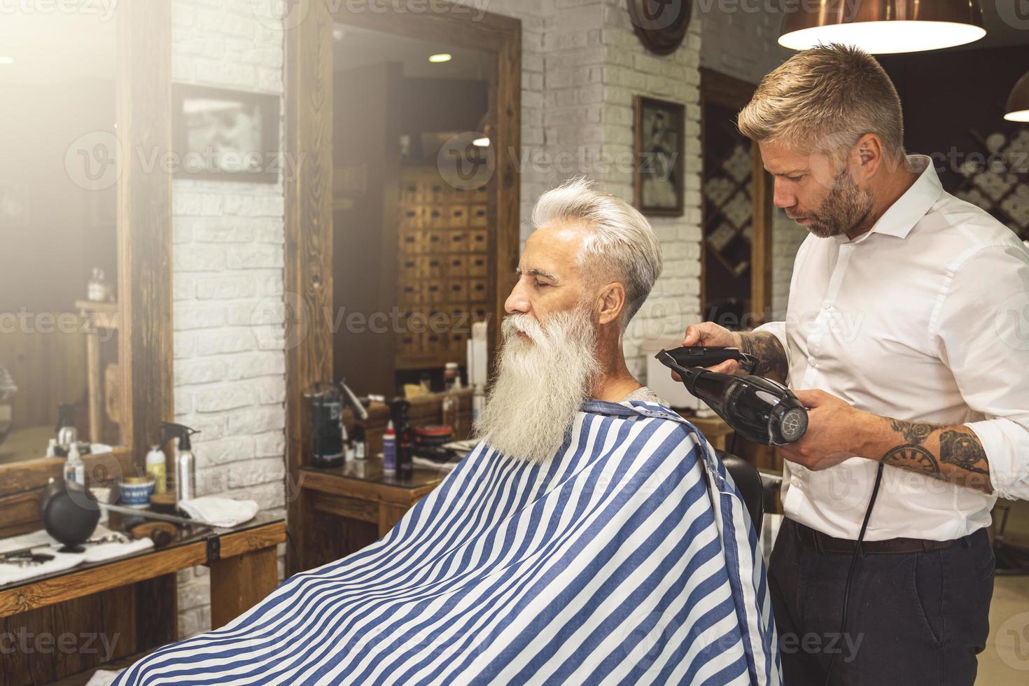 coiffeur faisant une coupe de cheveux élégante pour un beau vieil homme photo