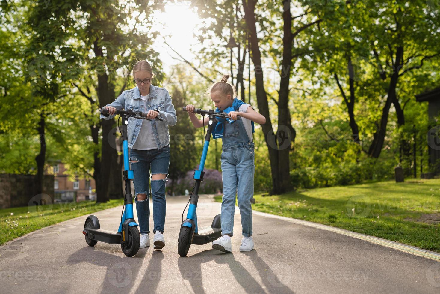 mère et fille faisant du scooter électrique dans le parc de la ville photo