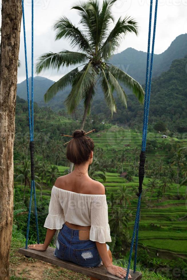 femme sur des balançoires avec une belle vue sur les rizières en terrasses de bali. photo