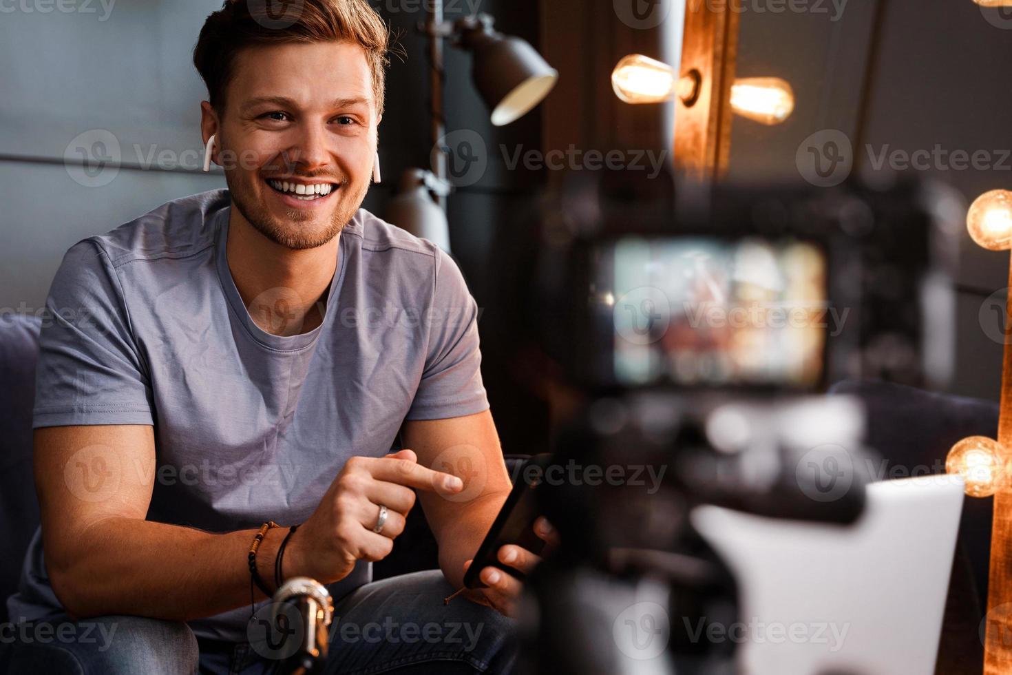 jeune blogueur souriant est assis devant un ordinateur portable photo