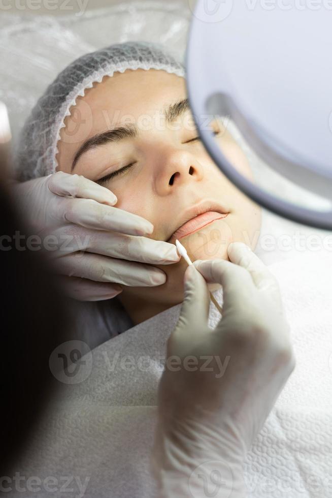 maquilleuse permanente et sa cliente pendant la procédure de rougissement des lèvres photo