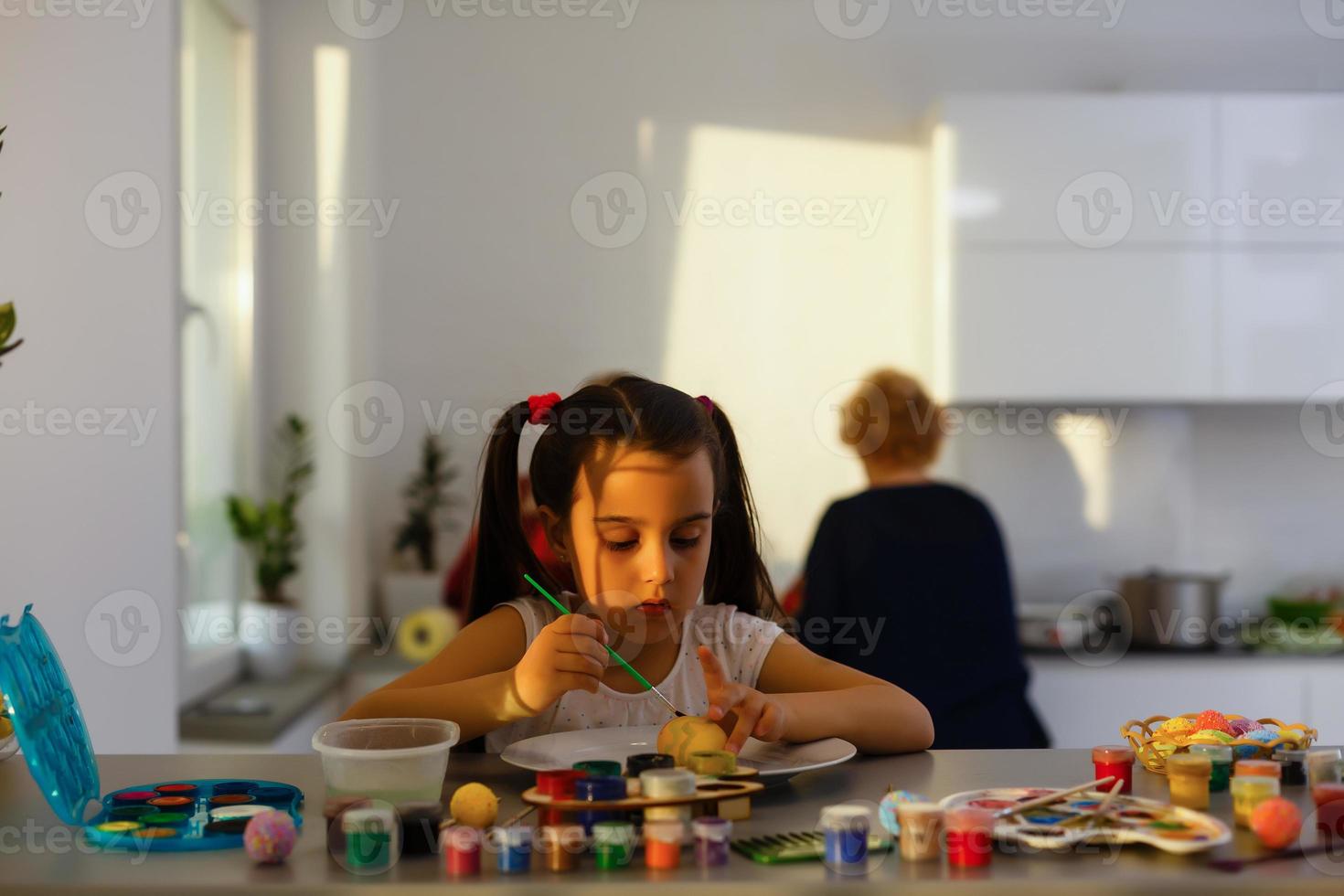 petite fille s'amusant à peindre des oeufs de pâques photo