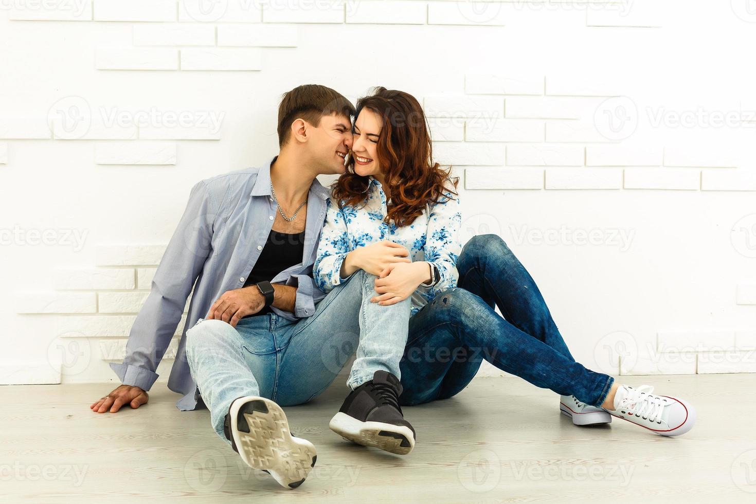 l'homme et la femme heureux s'assoient sur le fond du mur blanc photo