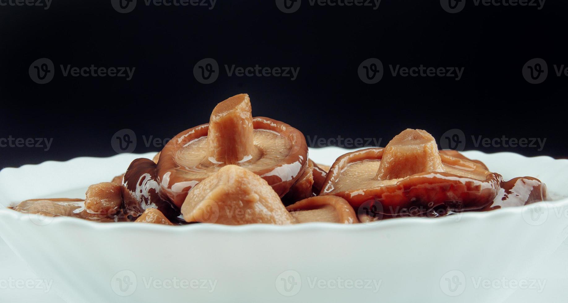 une assiette blanche de champignons marinés . nourriture de village saine. champignon de lait noir mariné . photo