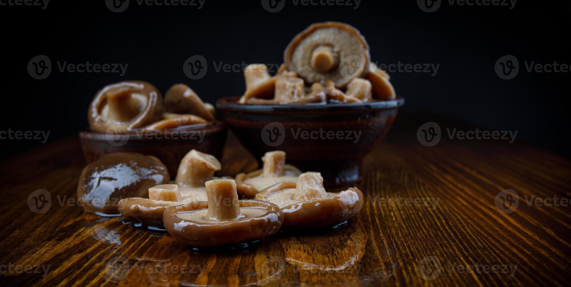 les champignons marinés dans des tasses en argile se tiennent sur une table en bois. champignons salés. cuisine rustique. photo