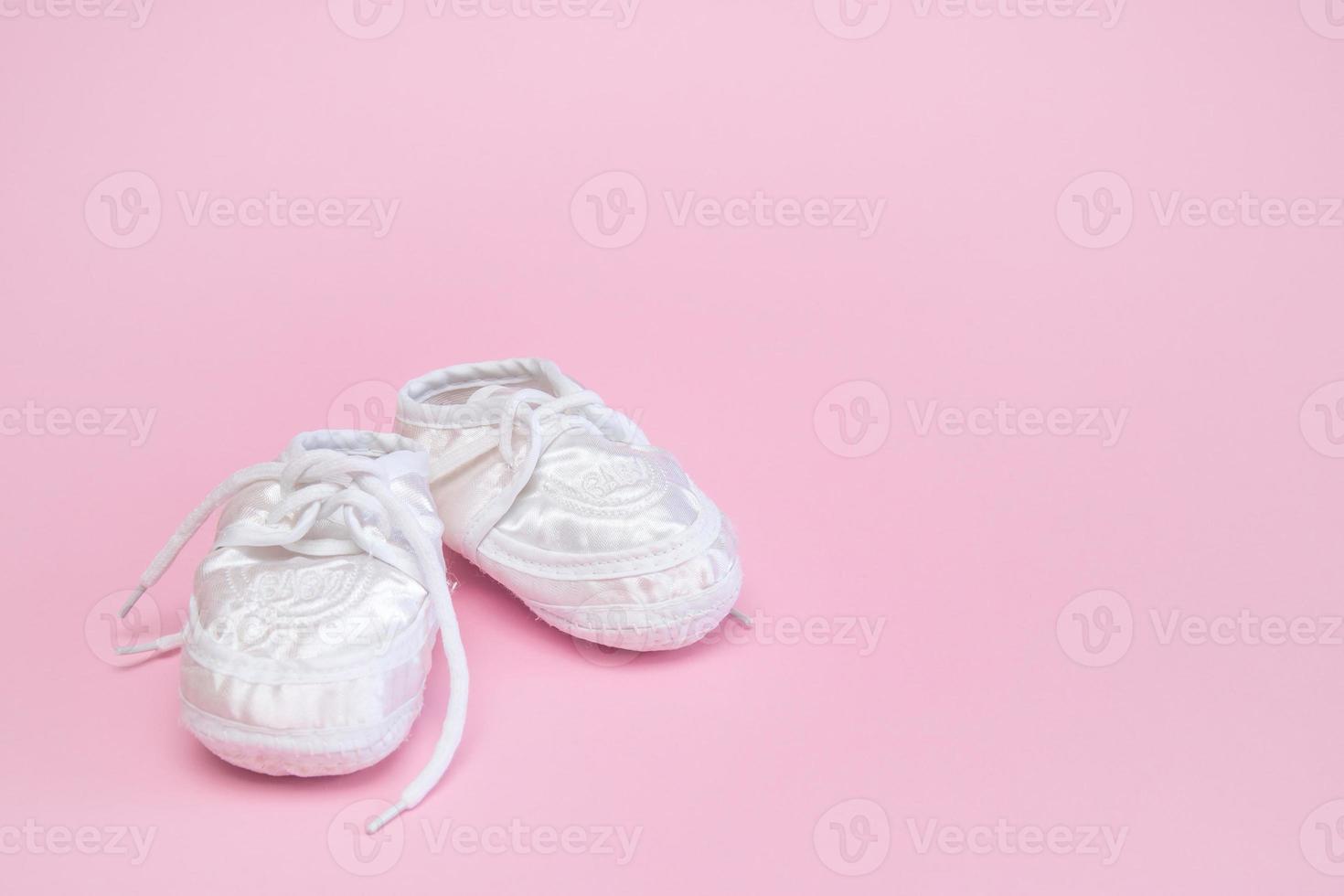 chaussons pour un nouveau-né sur un espace de copie de fond rose photo
