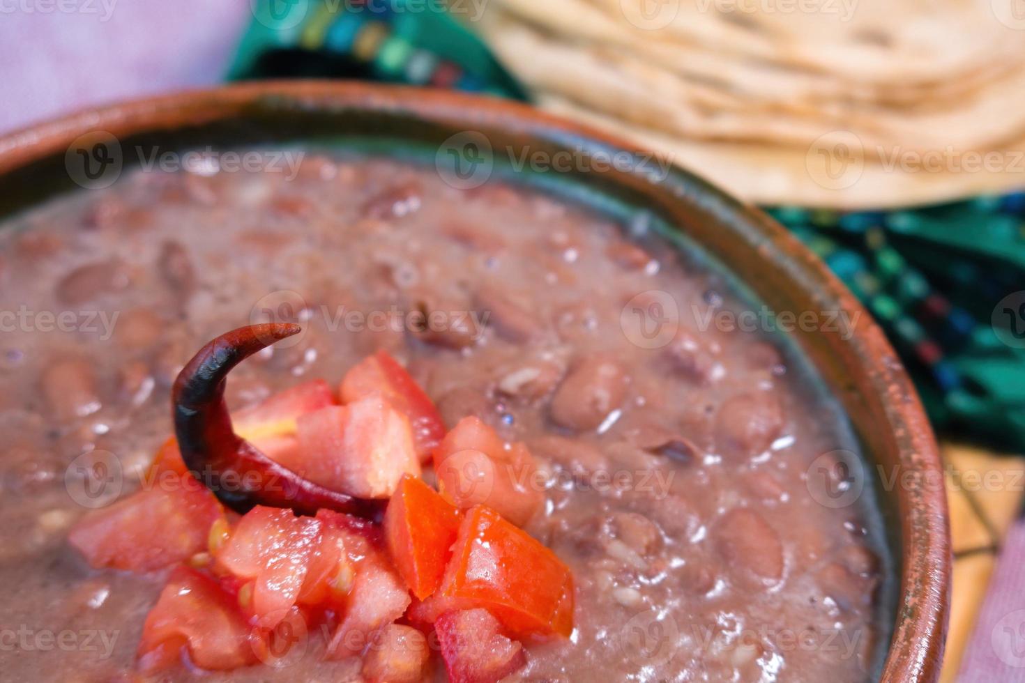 haricots cuits dans un plat d'argile avec tomate et tortillas, plat pauvre mexicain photo