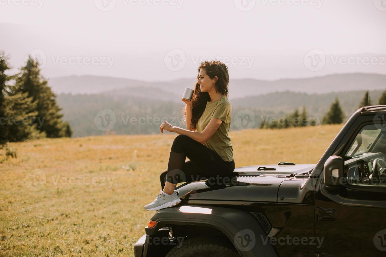 jeune femme se reposant sur un capot de véhicule tout-terrain à la campagne photo