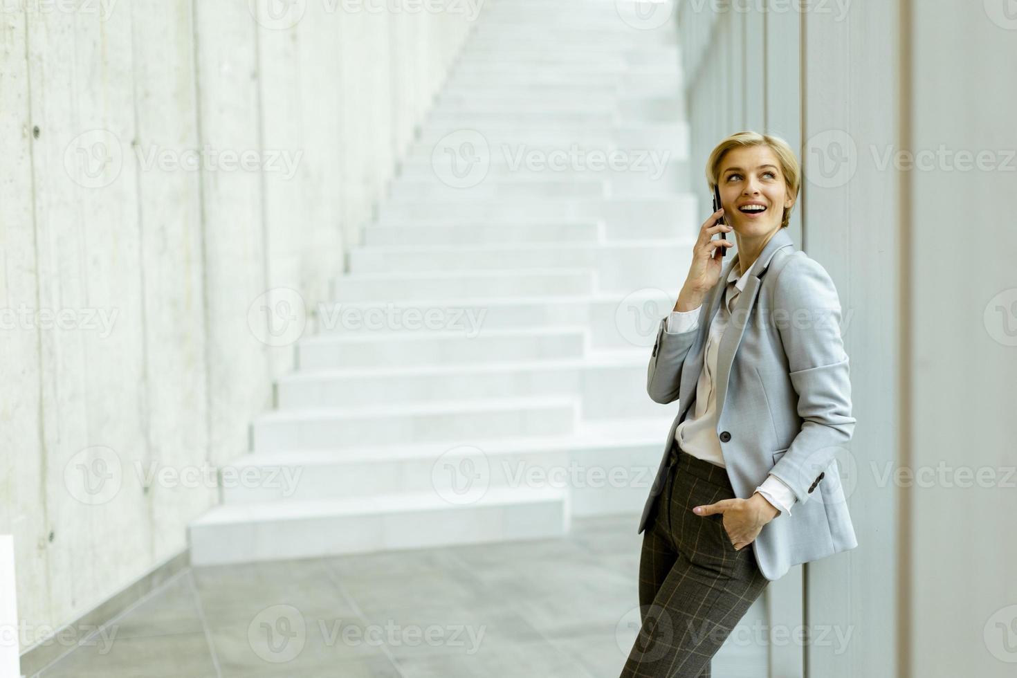 femme d'affaires utilisant un téléphone portable dans un couloir de bureau moderne photo