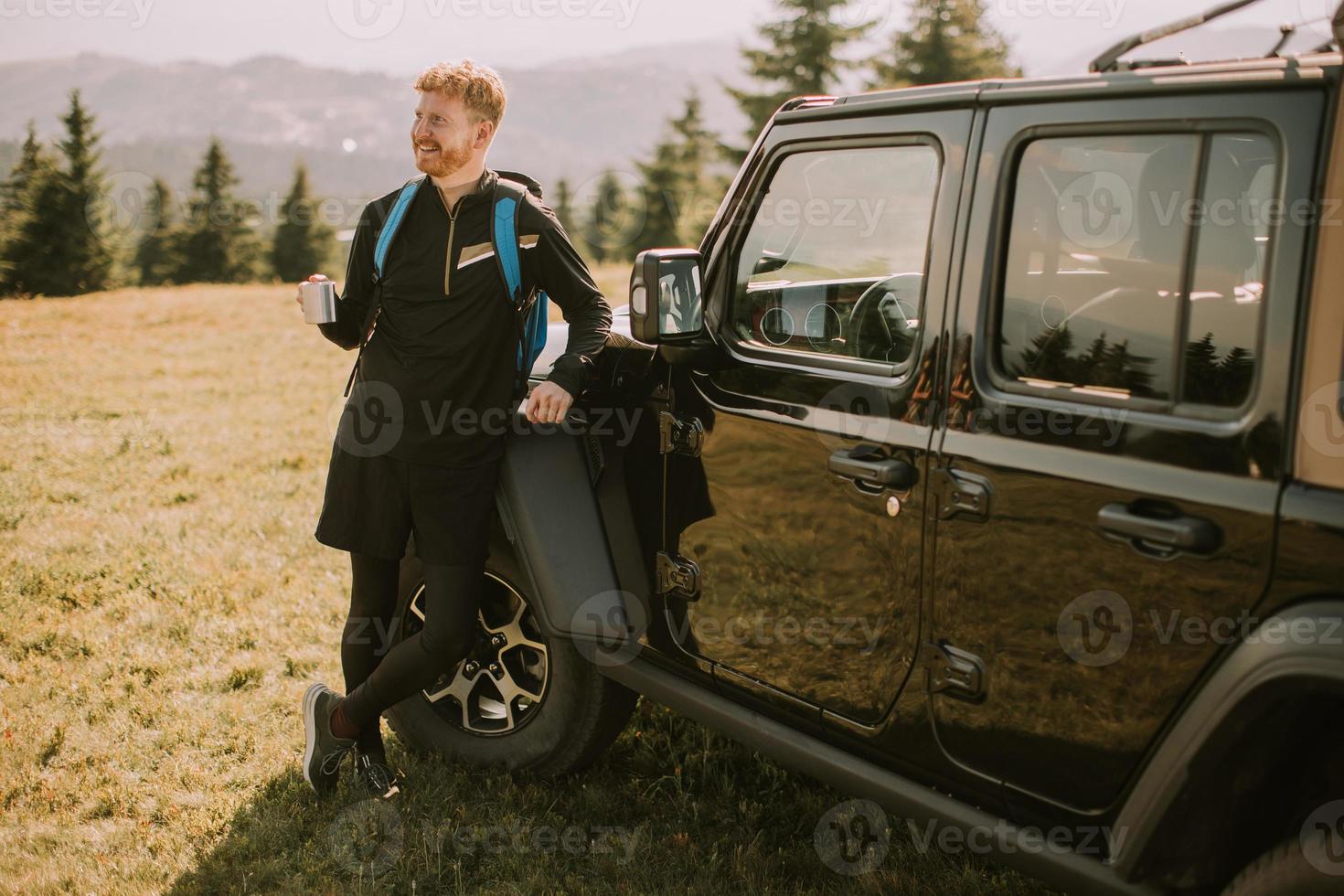 jeune homme se reposant sur un capot de véhicule tout-terrain à la campagne photo