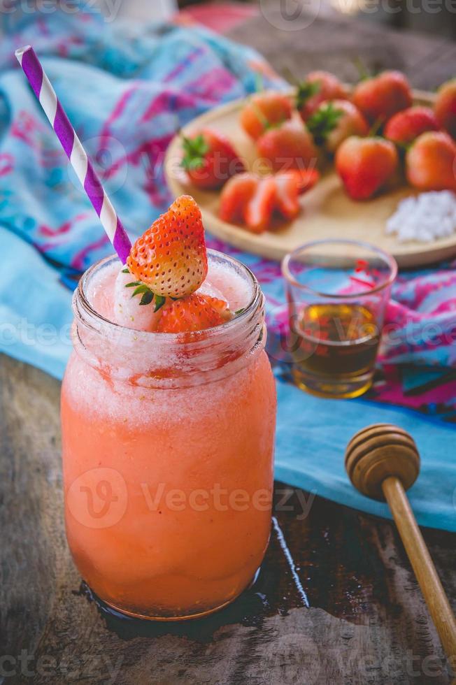 jus de smoothie aux fraises, sur le miel de garniture savoureux pour l'été sur table en bois, jus d'eau douce pour la santé photo