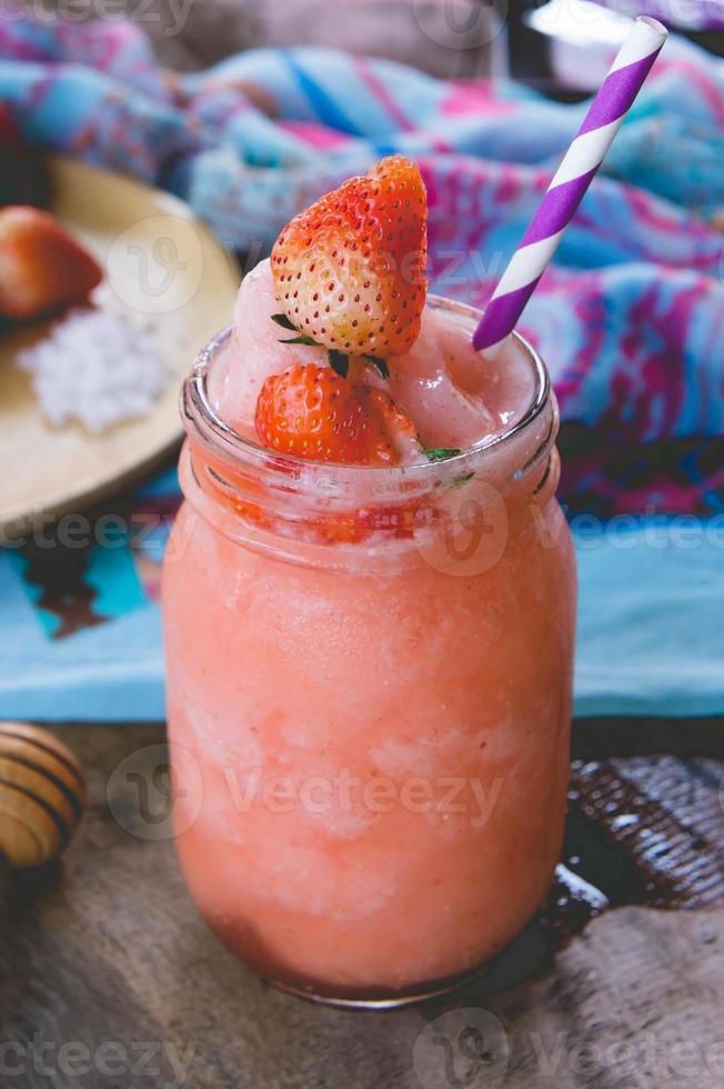 jus de smoothie aux fraises, sur le miel de garniture savoureux pour l'été sur table en bois, jus d'eau douce pour la santé photo