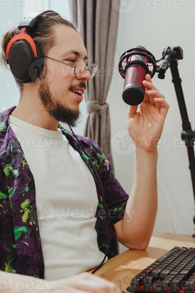 jeune homme blogueur utilisant un casque et un microphone à condensateur pendant le flux de podcast en ligne photo