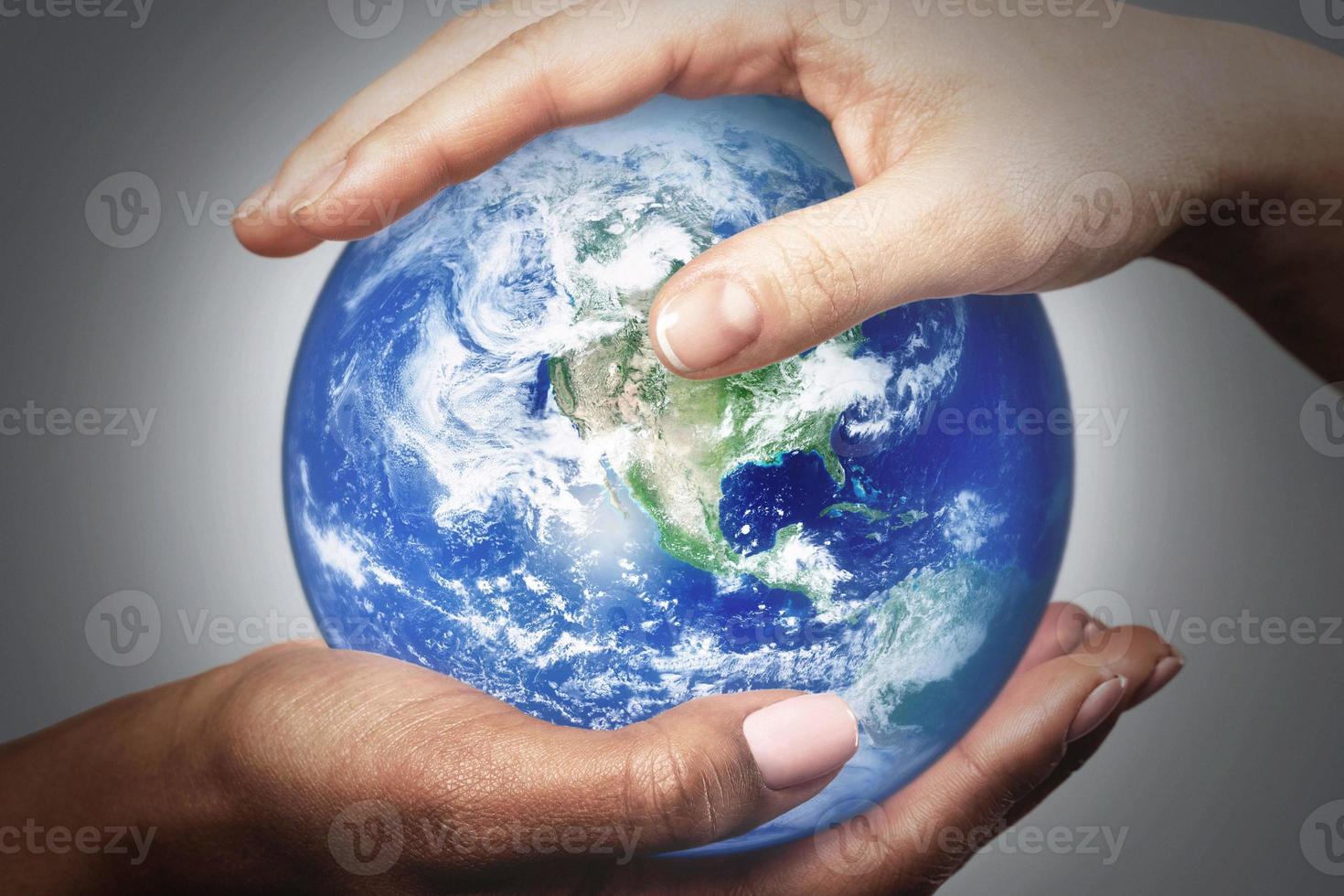 mains de femmes africaines et caucasiennes tenant un globe terrestre. éléments de cette image fournis par la nasa. photo