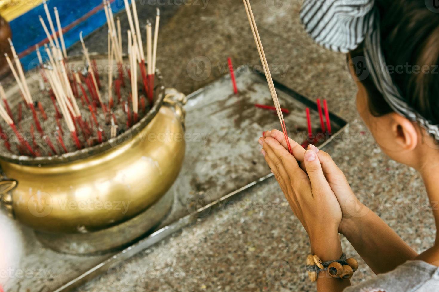 jeune femme touriste priant dans un temple bouddhiste devant l'encensoir. photo