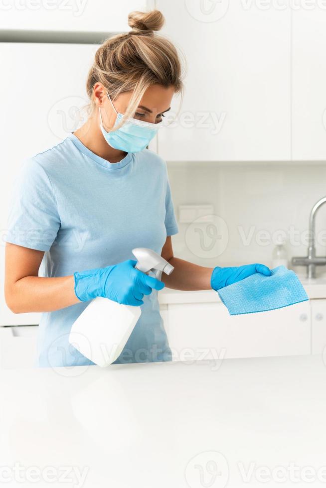 femme travailleuse portant un masque de prévention et des gants pendant le nettoyage de l'appartement photo