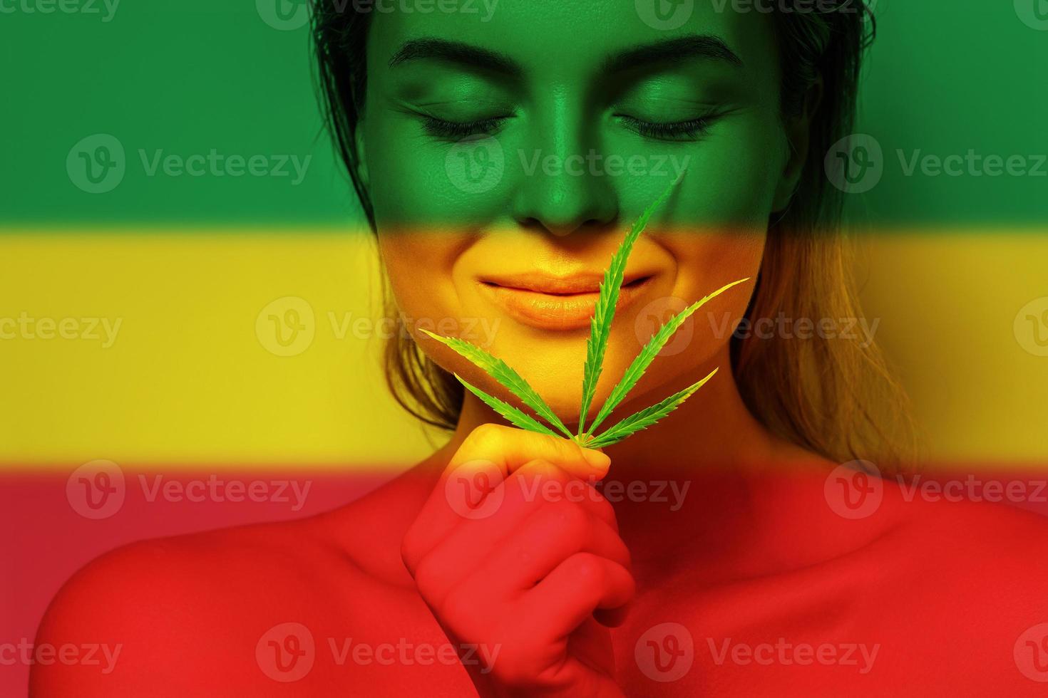 belle femme avec une feuille de cannabis aux couleurs du drapeau rastafari photo