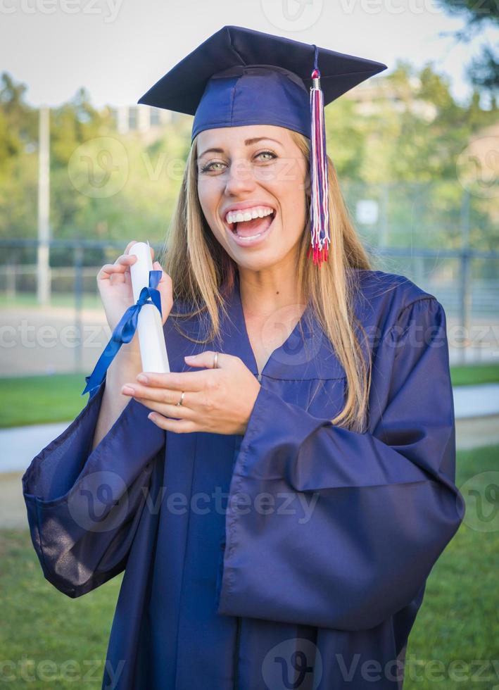 jeune femme expressive titulaire d'un diplôme en bonnet et robe photo