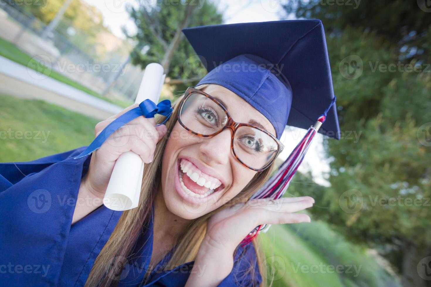 jeune femme expressive titulaire d'un diplôme en bonnet et robe photo