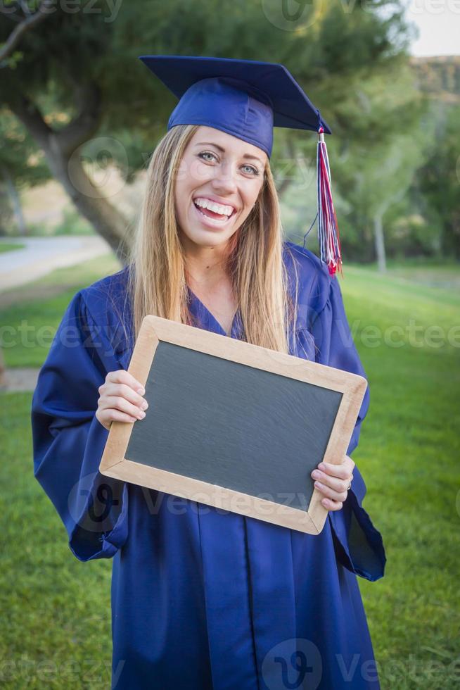 femme tenant un diplôme et un tableau blanc portant une casquette et une robe photo