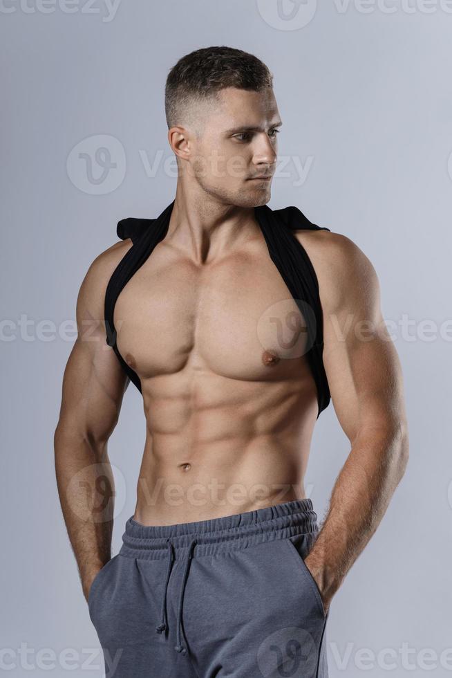 jeune bodybuilder montrant son corps musclé sur fond gris photo