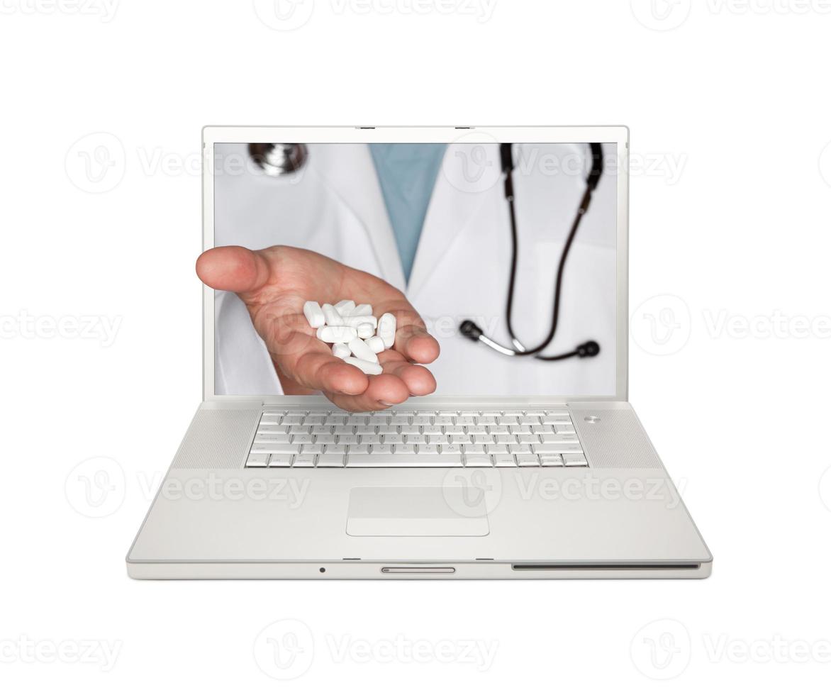 médecin remettant des pilules à travers l'écran d'un ordinateur portable photo