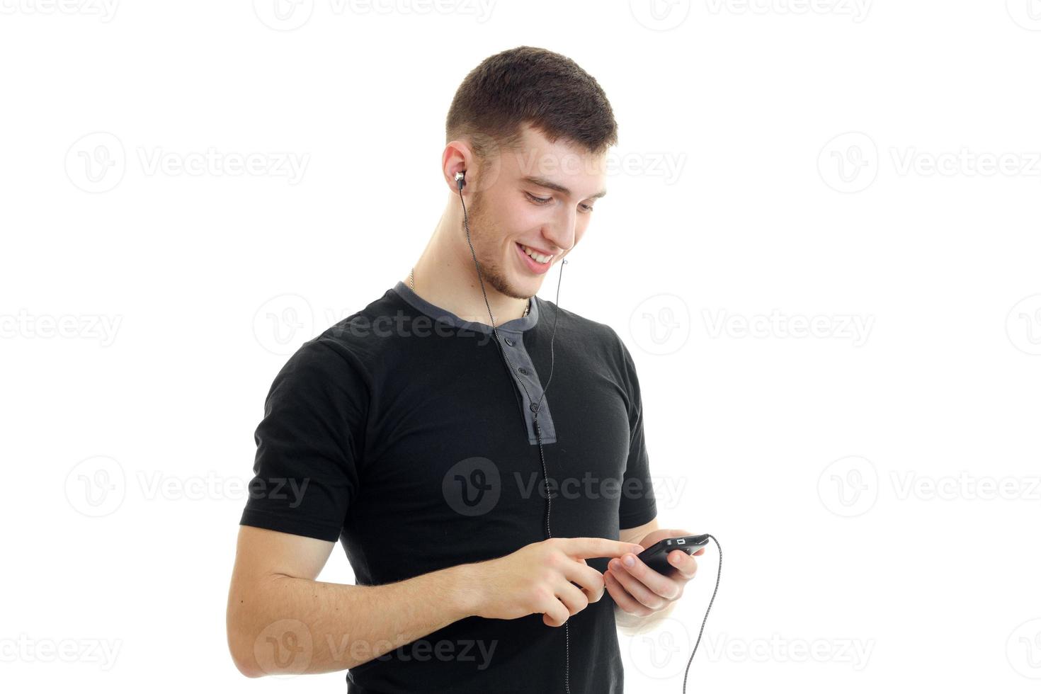 gars en chemise noire souriant et regardant le téléphone dans les mains photo