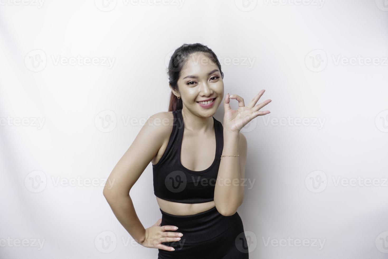 femme asiatique sportive excitée portant un vêtement de sport donne un geste de la main ok isolé par un fond blanc photo