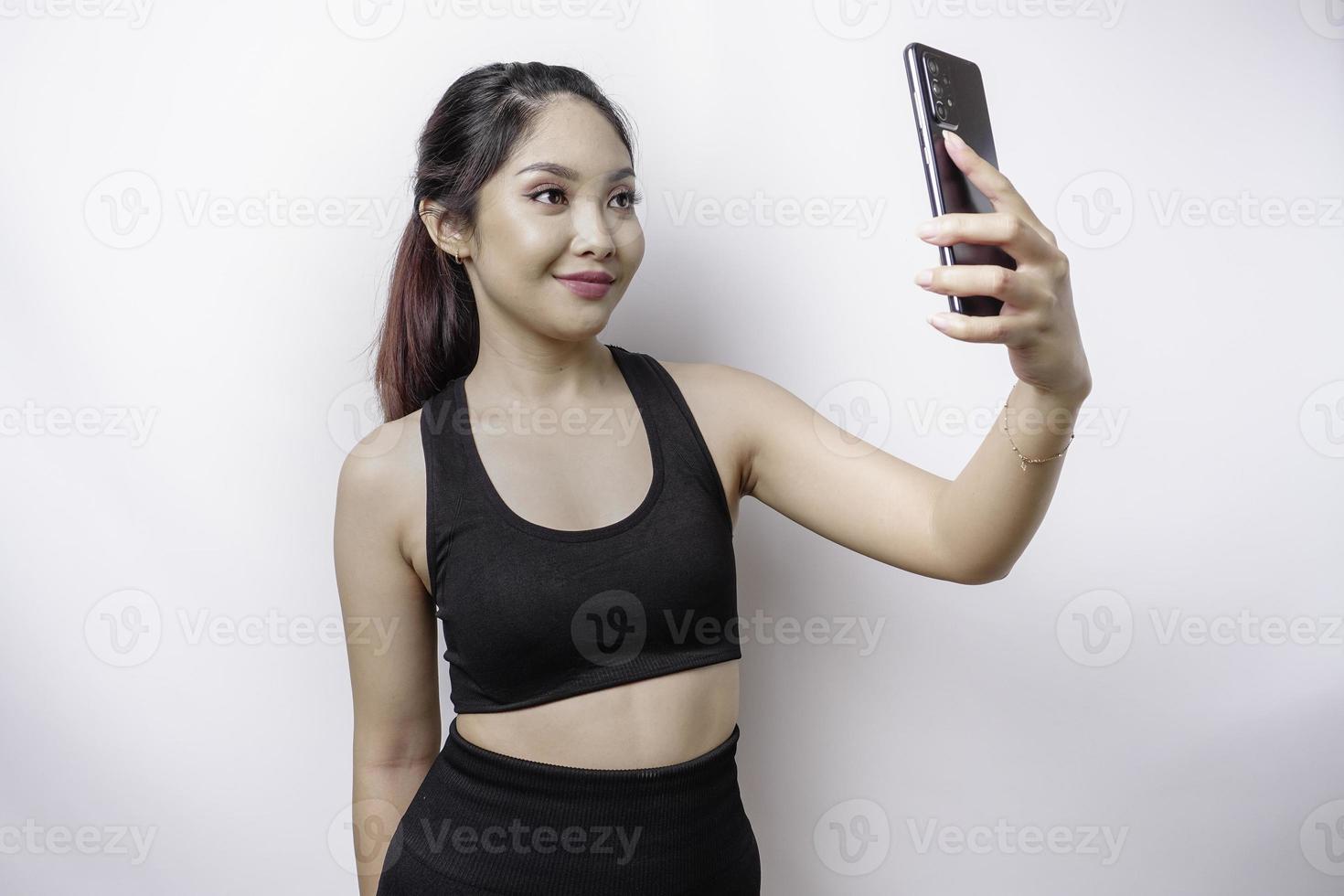 un portrait d'une femme asiatique sportive portant un vêtement de sport et tenant son téléphone, isolée sur fond blanc photo