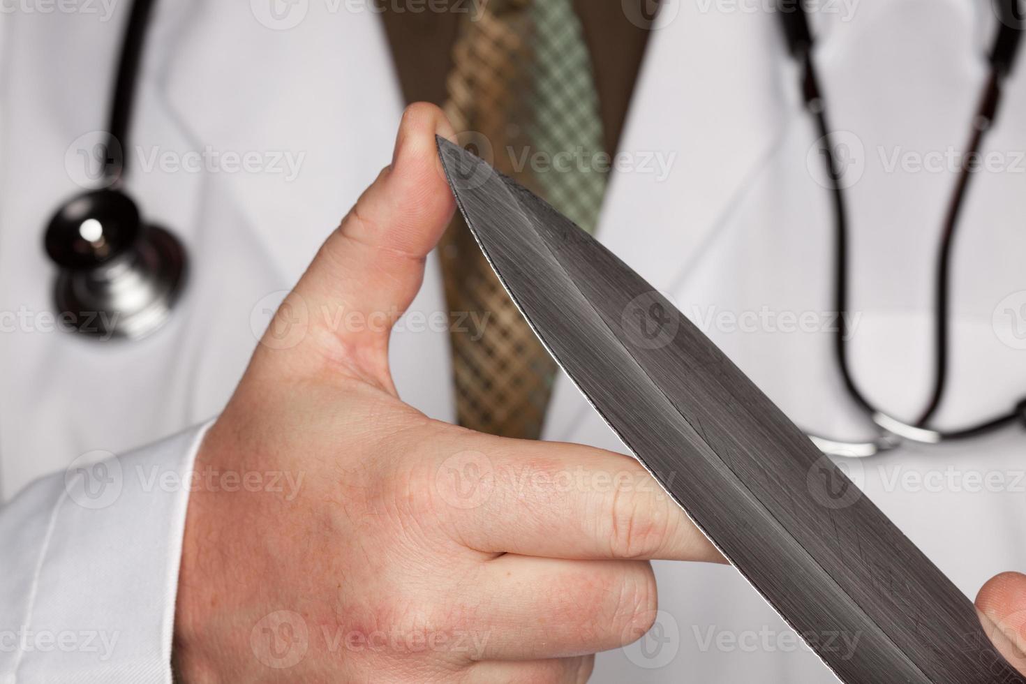 médecin avec stéthoscope tenant un grand couteau photo