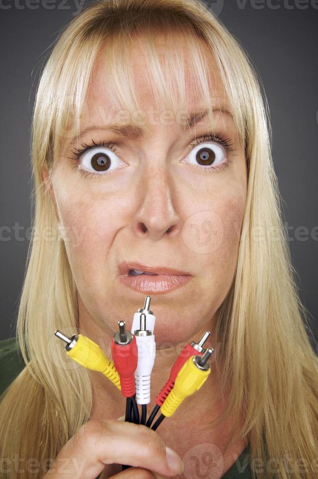 femme confuse tenant des câbles électroniques photo