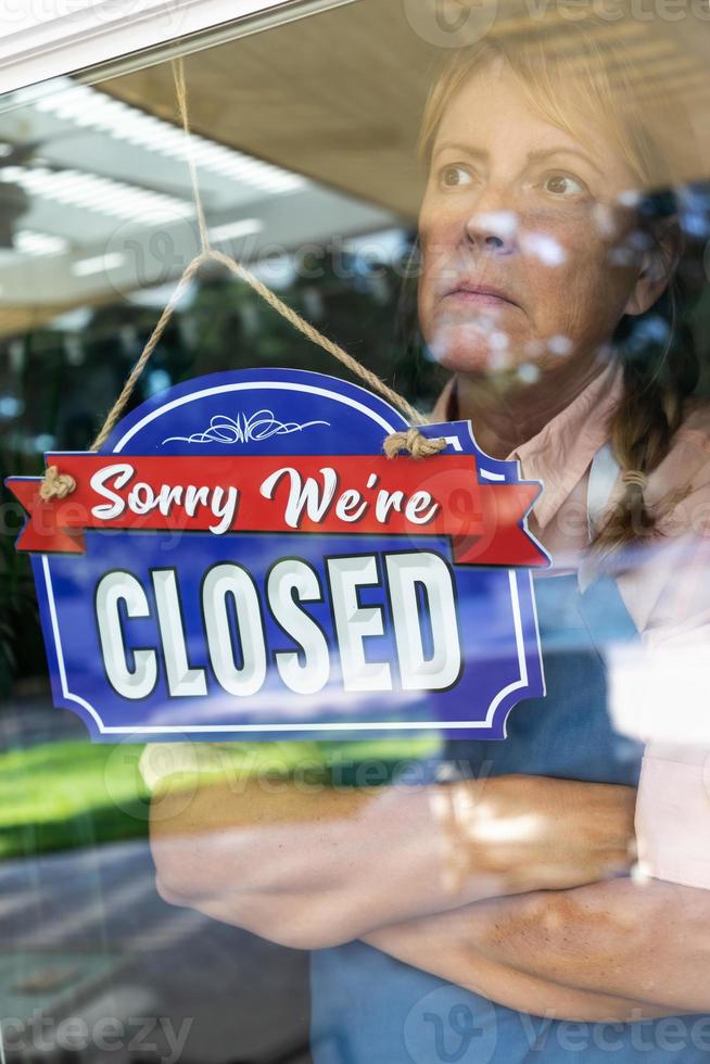femme triste propriétaire d'un magasin tournant le signe pour fermer la fenêtre photo