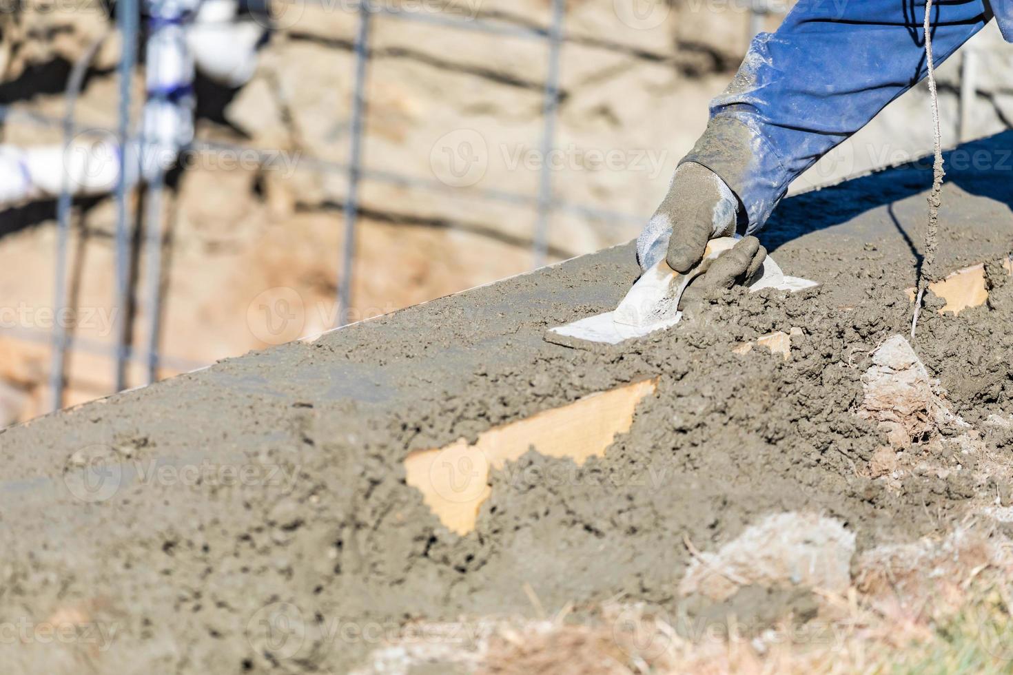 Ouvrier en construction de piscine travaillant avec un flotteur en bois sur du béton humide photo