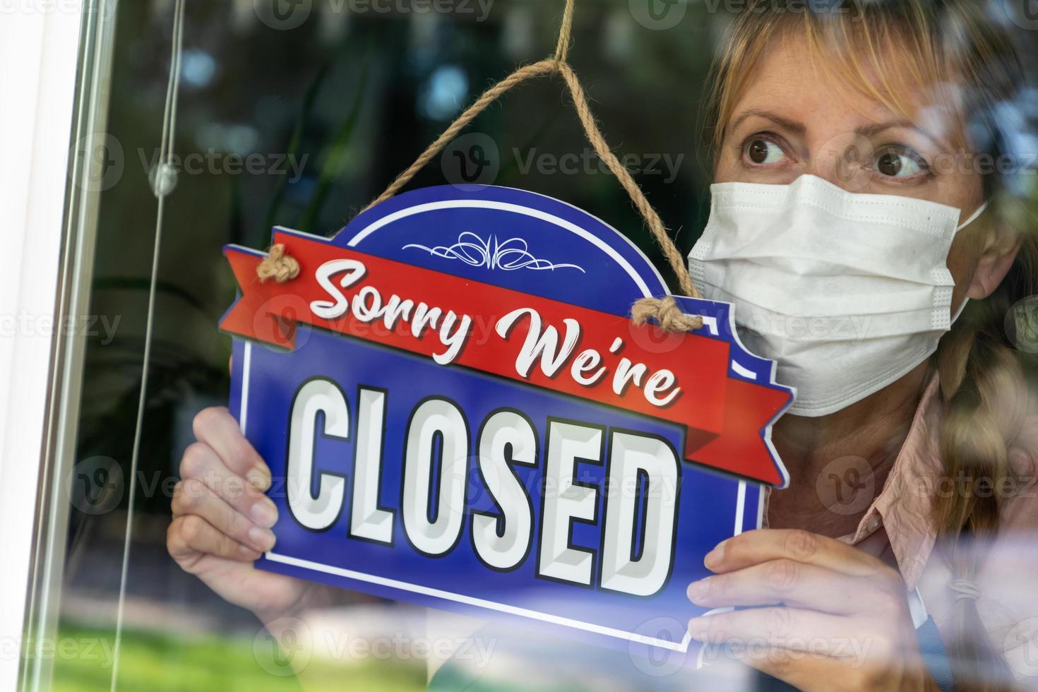 femme propriétaire d'un magasin portant un masque médical tournant le signe pour fermer la fenêtre photo