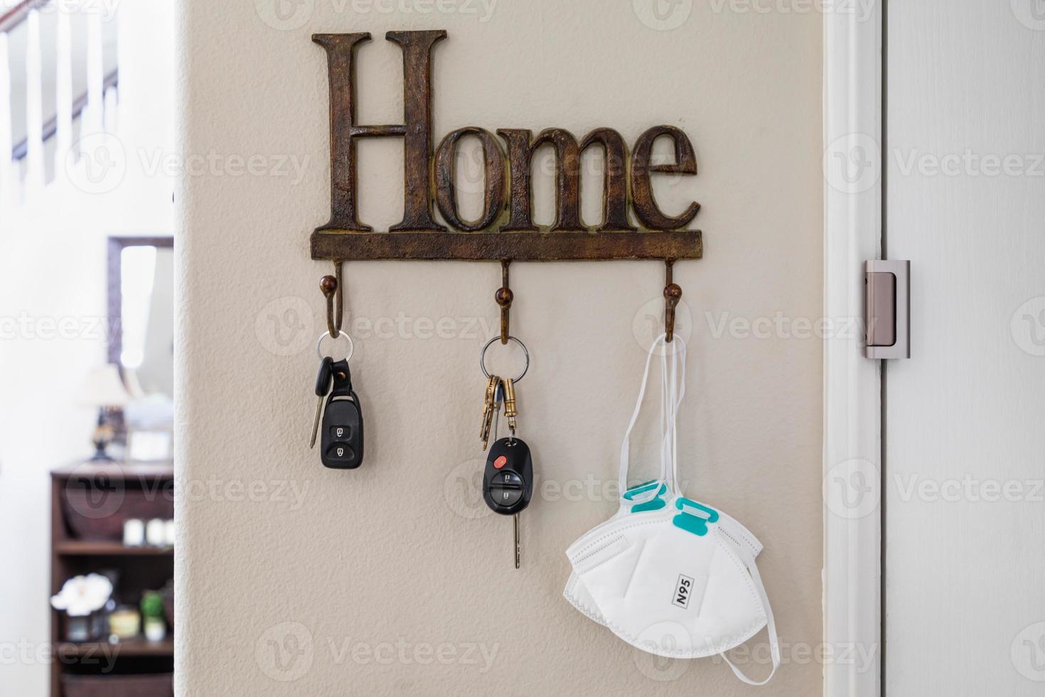 porte-clés à la maison à côté de la porte avec clés et masque médical pendant la pandémie de coronavirus. photo