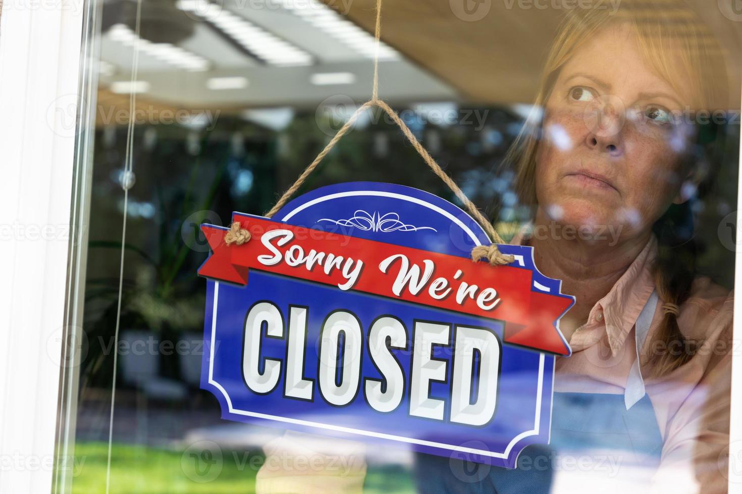 femme triste propriétaire d'un magasin tournant le signe pour fermer la fenêtre photo