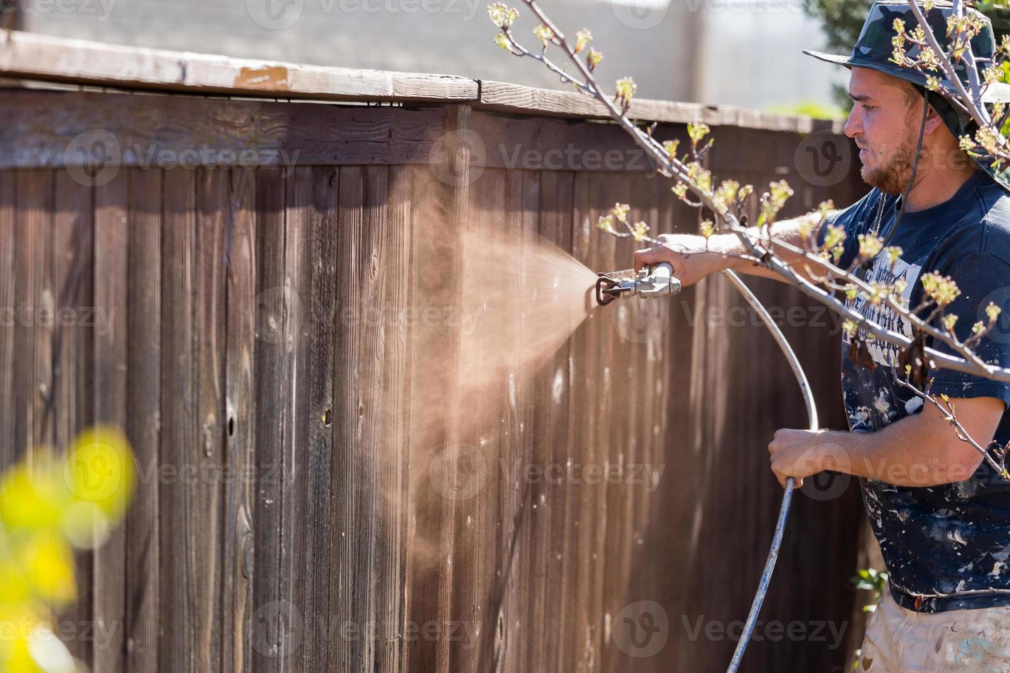 peintre professionnel pulvérisant une clôture de jardin avec tache photo