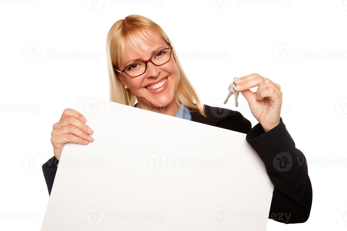 jolie blonde tenant des clés et un panneau blanc vierge photo