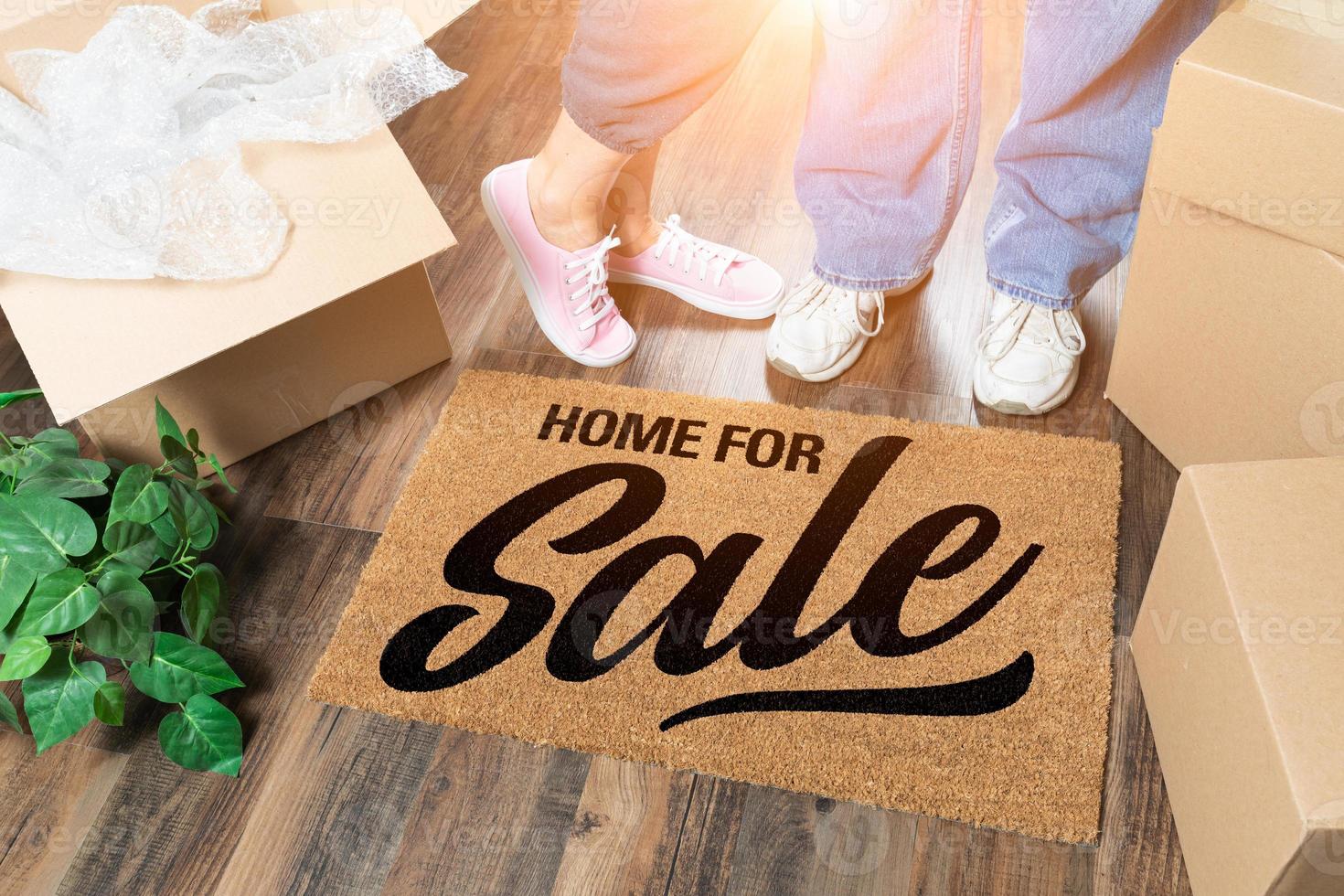 homme et femme debout près de la maison à vendre tapis de bienvenue, boîtes de déménagement et plante photo