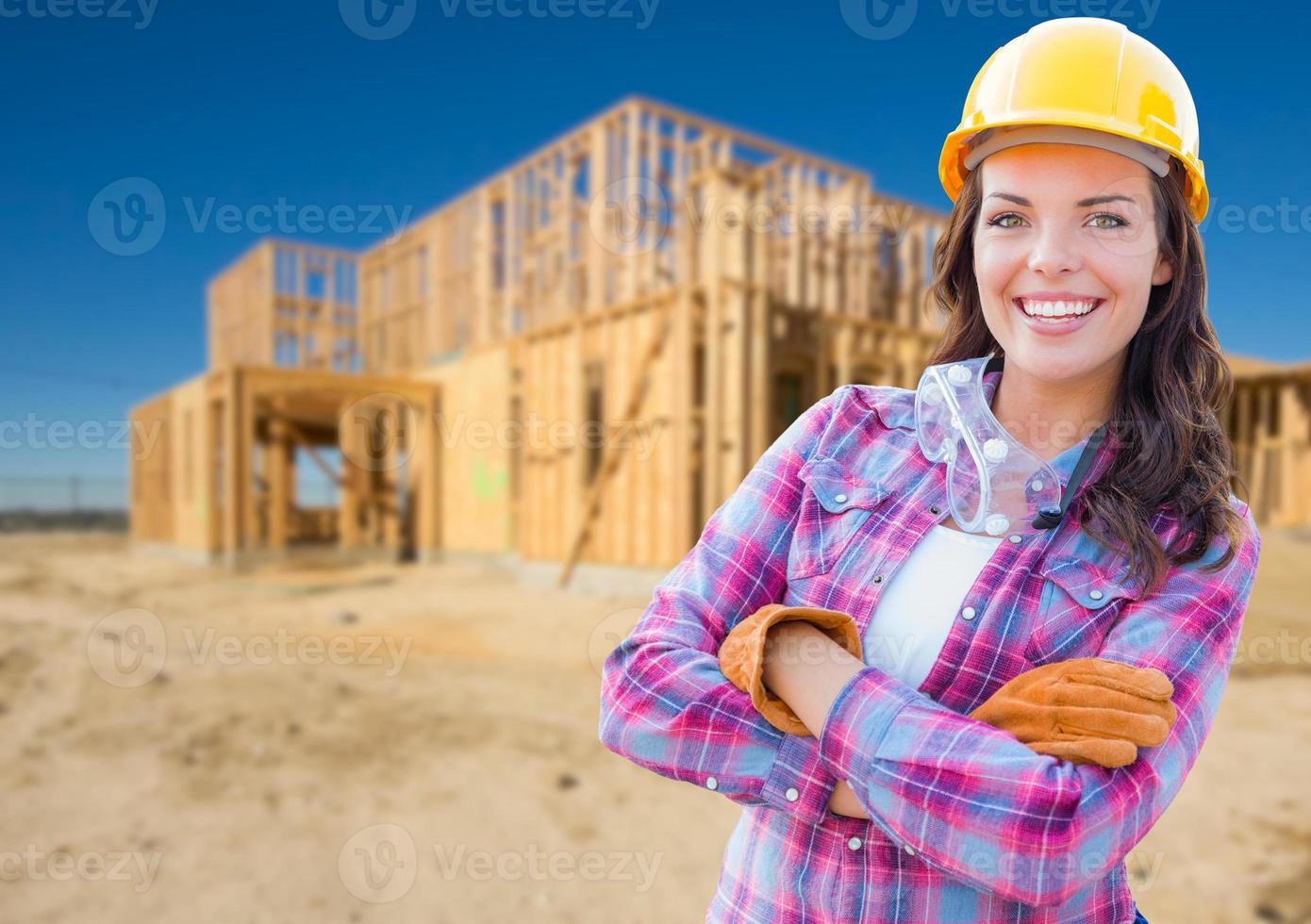 jeune ouvrière du bâtiment séduisante portant des gants, un casque et des lunettes de protection sur le chantier photo