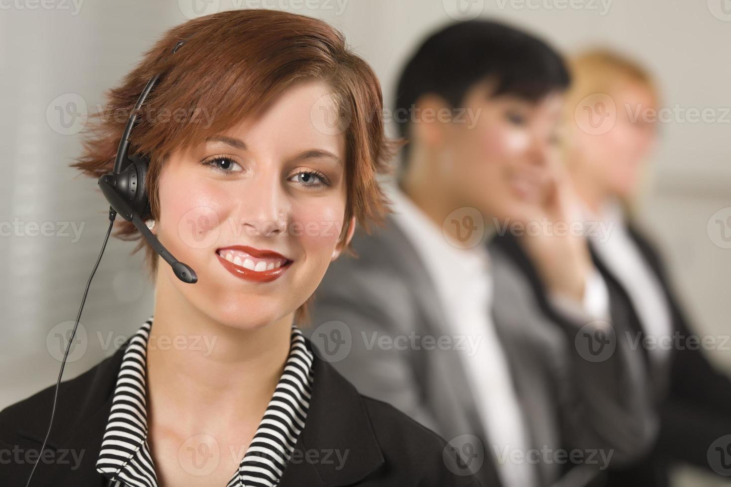 jolie femme d'affaires aux cheveux rouges avec casque et collègues photo