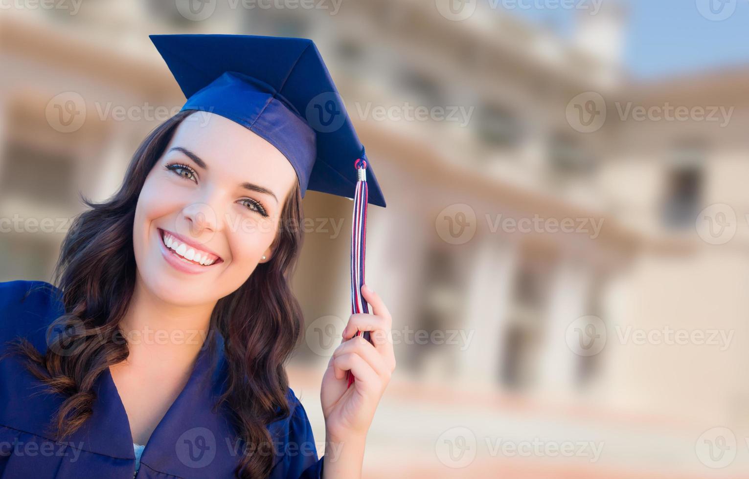 heureuse diplômée métisse femme en bonnet et robe célébrant sur le campus. photo