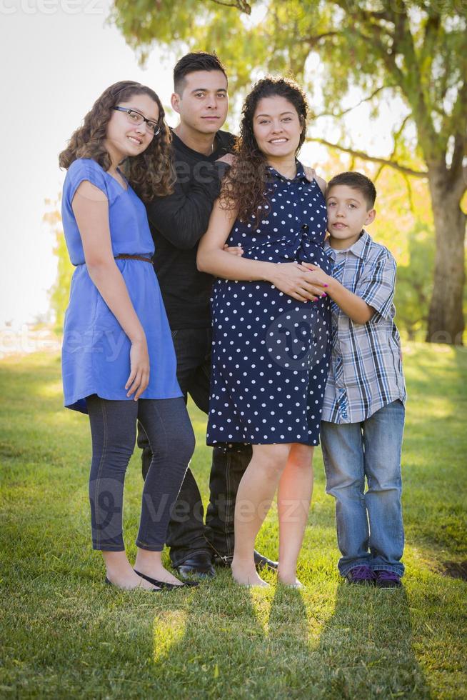 heureuse famille hispanique attrayante avec leur mère enceinte à l'extérieur photo