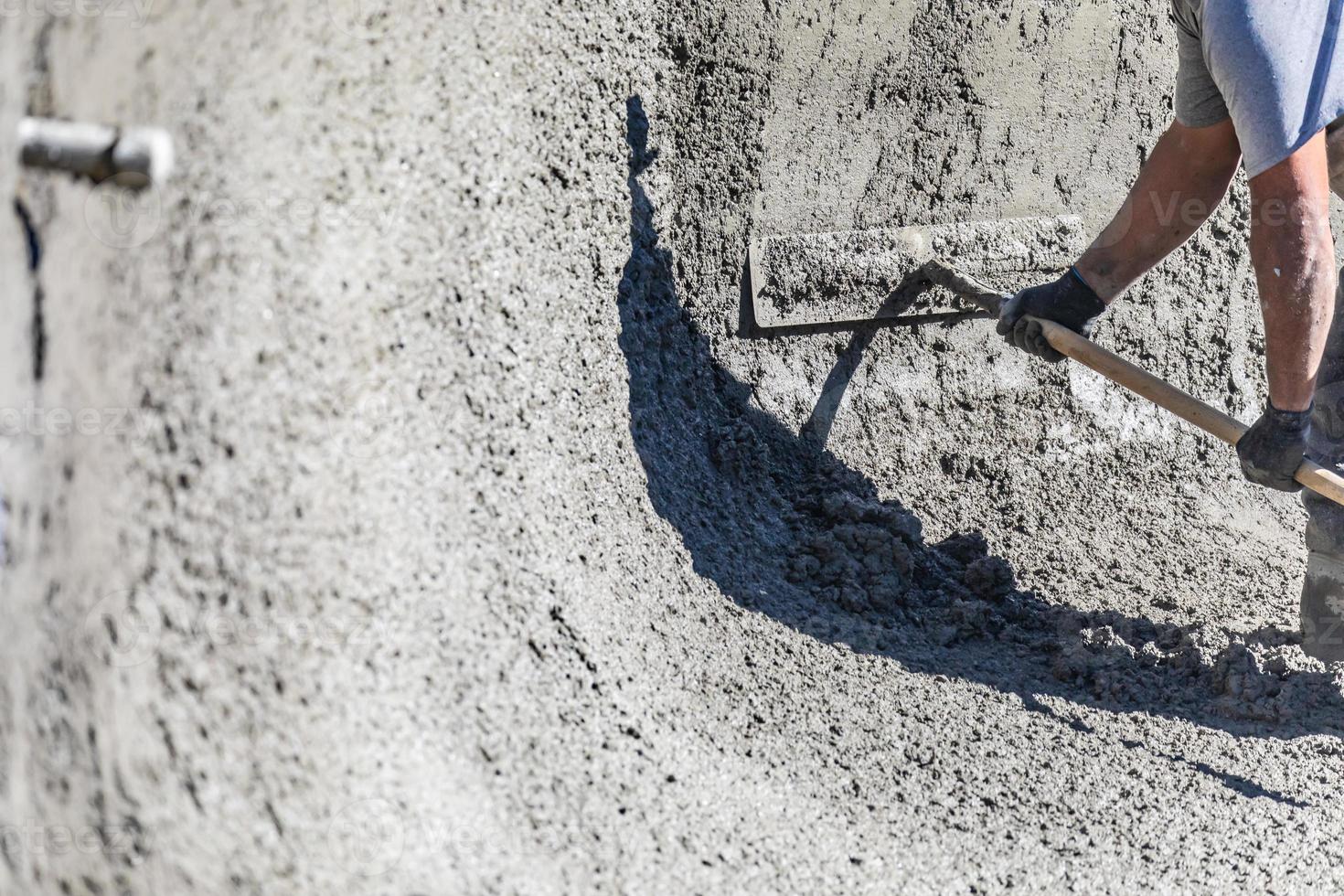 Ouvrier en construction de piscine travaillant avec un bullfloat sur du béton humide photo